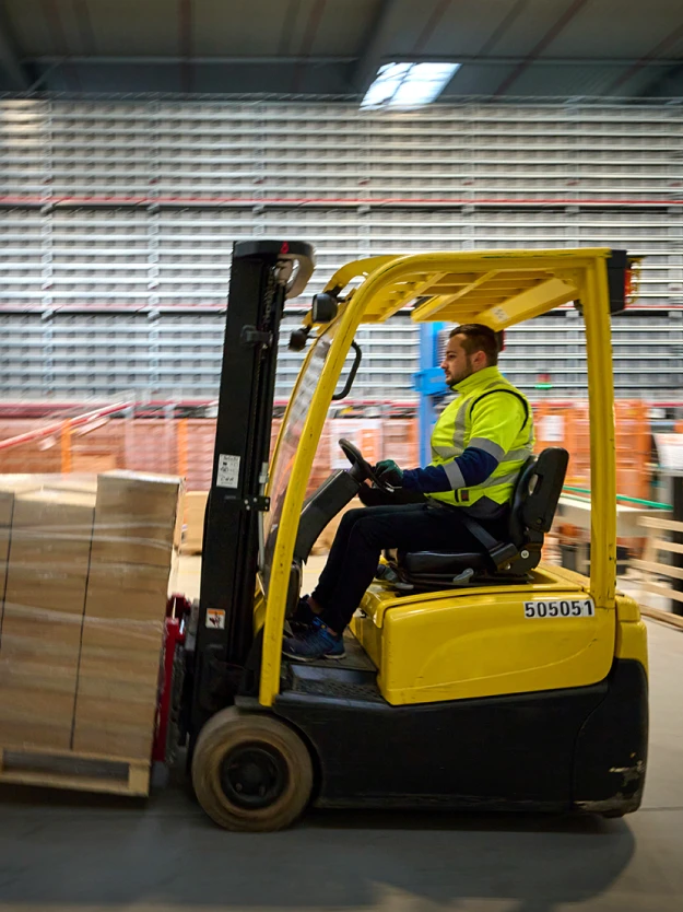 Un cariste CGR qui conduit un chariot élévateur dans un entrepôt logistique