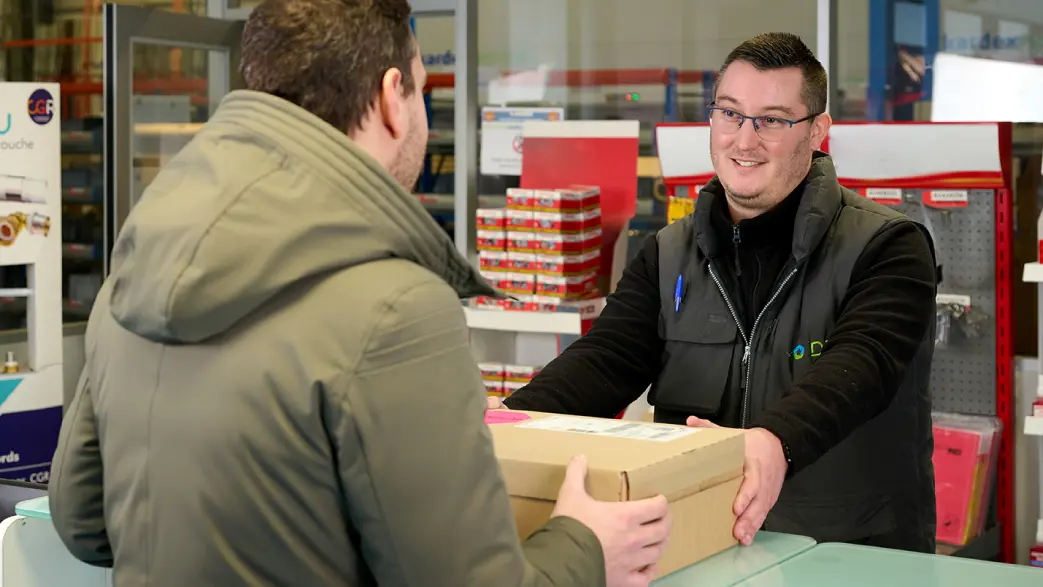 Image d'un vendeur comptoir d'une agence CGR-DBS qui sert un client au comptoir d'une agence